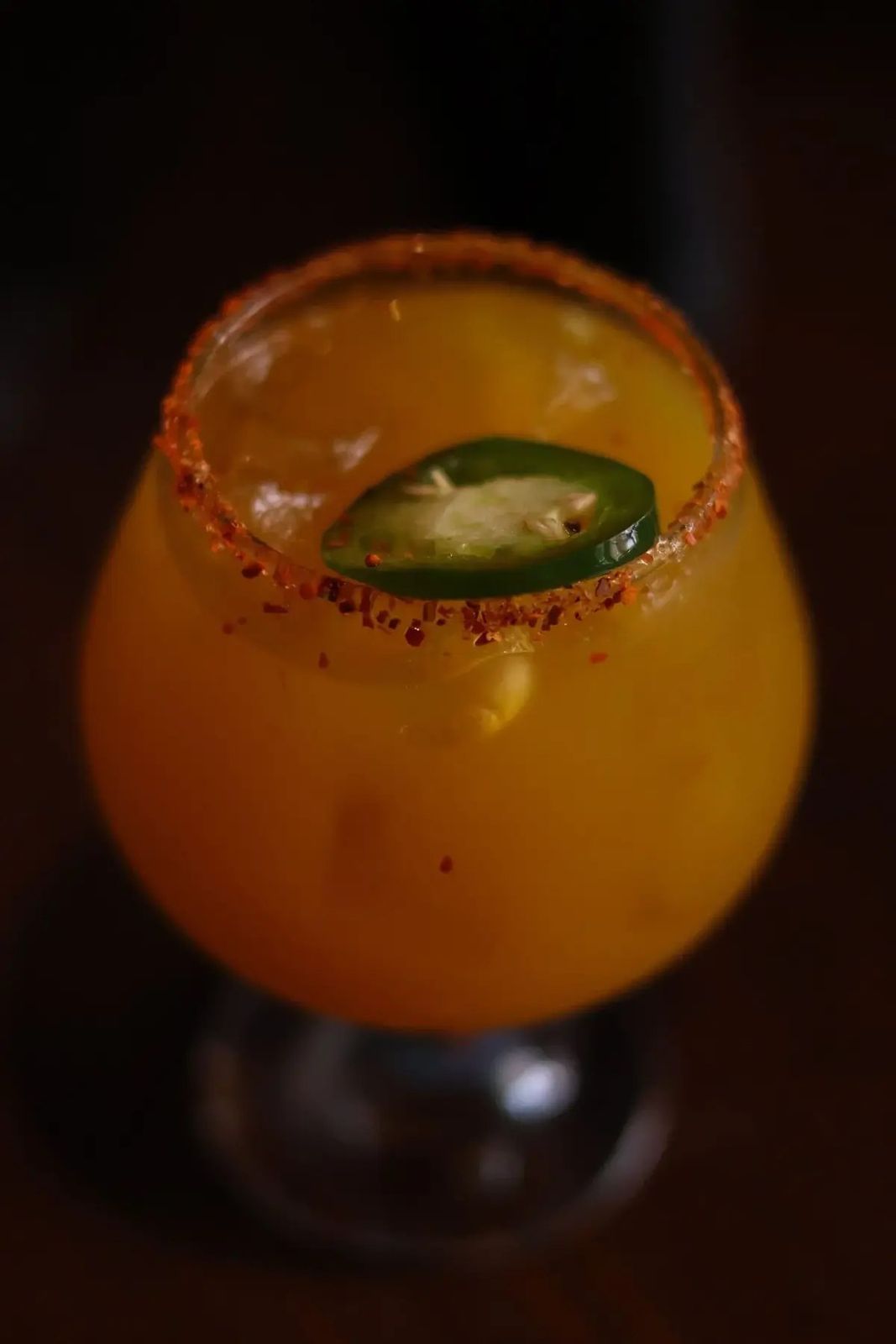 Orange cocktail with a chili-salt rim and jalapeño